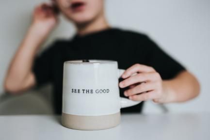 Niño con taza en la que se lee "See the good". Photo by Nathan Dumlao on Unsplash