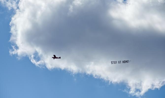 Avioneta con un cartel con el mensaje "Stay at home"