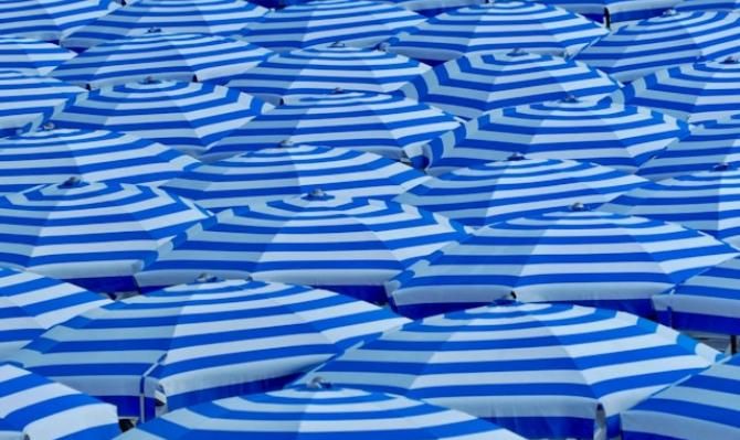 Mar de sombrillas azules en una playa. Foto de Belinda Fewings en Unsplash