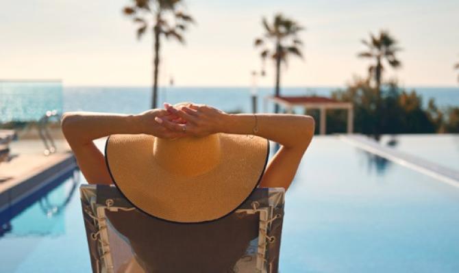 Mujer con pamela descansando frente a una piscina