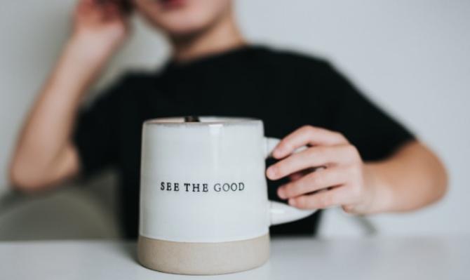 Niño con taza en la que se lee "See the good". Photo by Nathan Dumlao on Unsplash