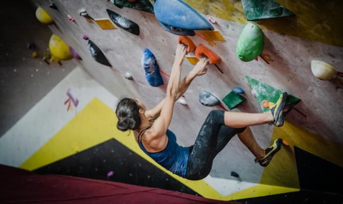 Mujer escalando en un rocódromo. Photo by Yns Plt on Unsplash