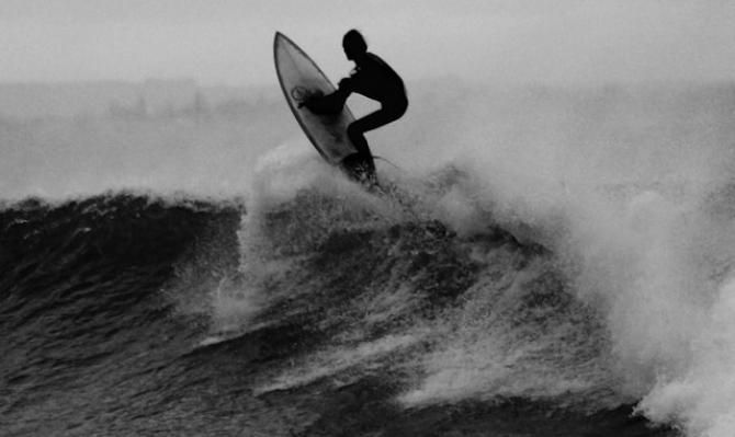 Surfista encima de una tabla sobre una ola. Photo by Alex Wigan on Unsplash