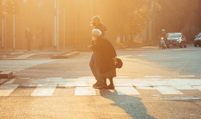 Hombre cruzando a señora mayor en un paso de cebra. Photo by Mikita Yo on Unsplash