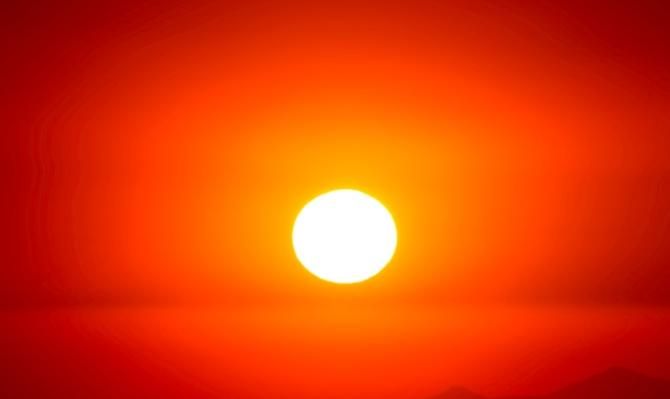 Sol ardiente sobre cielo rojo para ilustrar un artículo de CaixaBank Research sobre el impacto del cambio climático en la economía y en el turismo. Photo by Luis Graterol on Unsplash