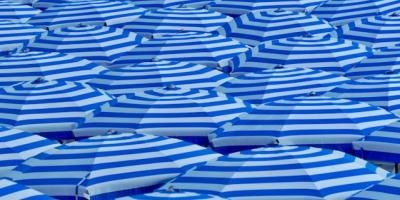 Mar de sombrillas azules en una playa. Foto de Belinda Fewings en Unsplash