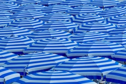 Mar de sombrillas azules en una playa. Foto de Belinda Fewings en Unsplash