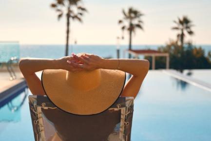 Mujer con pamela descansando frente a una piscina