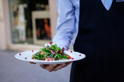 Camarero con un plato de ensalada en la mano. Photo by Lefteris Kallergis on Unsplash