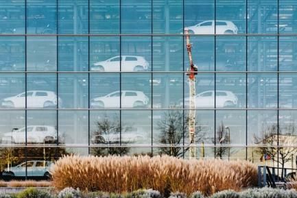 Edificio acristalado con coches nuevo almacenados en su interior. Photo by Maksym Kaharlytskyi on Unsplash