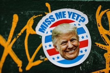 Pegatina con la cara de Donald Trump y el texto "Miss me yet" para ilustrar un artículo sobre política comercial estadounidense en el Informe Mensual 09/2026 de CaixaBank Research