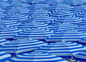 Mar de sombrillas azules en una playa. Foto de Belinda Fewings en Unsplash