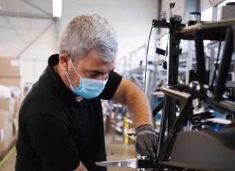 Trabajador con mascarilla manipulando maquinaria. Photo by Kumpan Electric on Unsplash